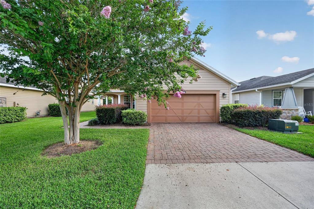 A single-story house with tan siding, a brick paver driveway, and a blooming crape myrtle — 4845 NW 35TH LANE ROAD, OCALA, FL