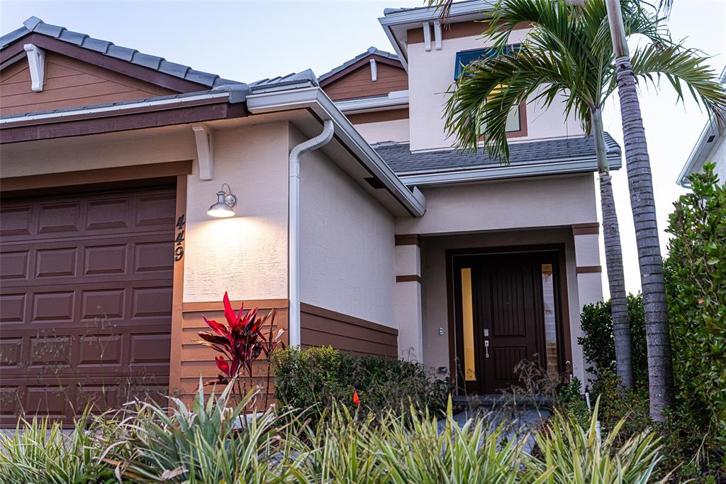A two-story house exterior features a brown garage door, a front entrance, and palm trees — 449 SE FASCINO CIRCLE, PORT ST LUCIE, FL