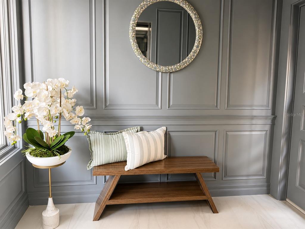 A wooden bench with two pillows sits against a gray paneled wall with a mirror — 3800 GULF BOULEVARD UNIT PH, ST PETERSBURG, FL