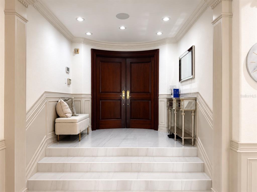 A foyer features a curved dark wood double door, marble steps, and wainscoting — 3800 GULF BOULEVARD UNIT PH, ST PETERSBURG, FL