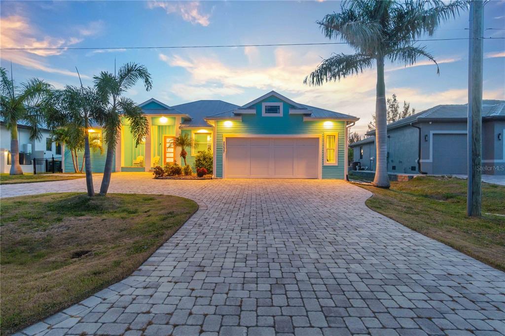 A teal single-story house with a paved driveway and palm trees at dusk — 8084 BURWELL CIRCLE, PORT CHARLOTTE, FL