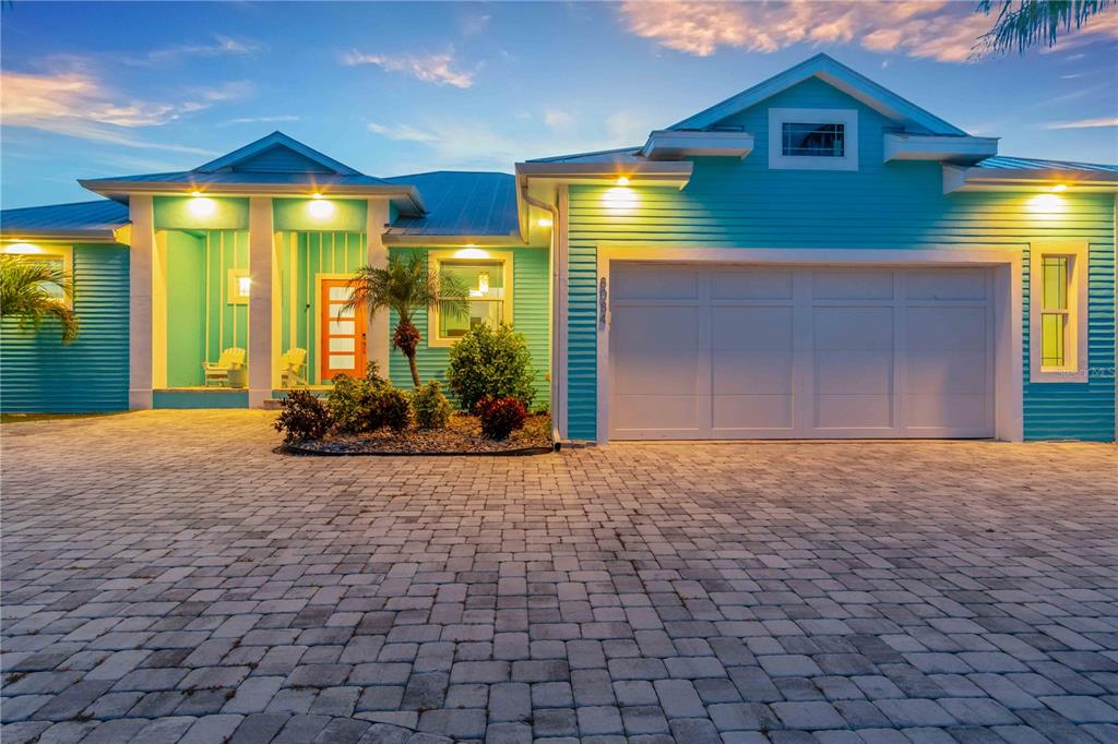 A turquoise house with a white garage door and a paved driveway at dusk — 8084 BURWELL CIRCLE, PORT CHARLOTTE, FL