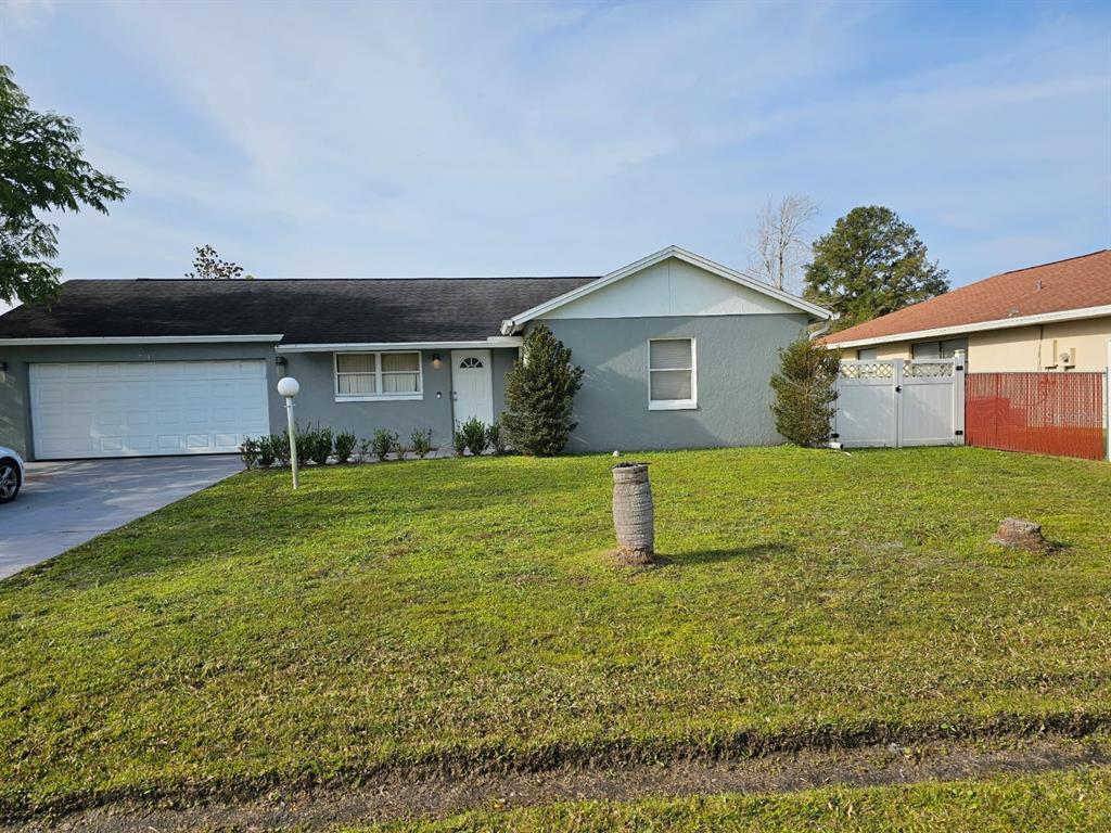 A single-story gray house with a white garage door and a front lawn — 724 DEL RAY DRIVE, KISSIMMEE, FL