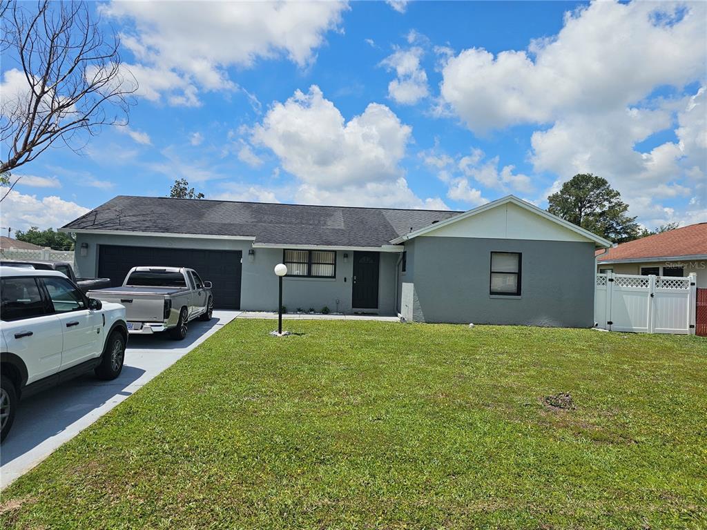 A gray single-story house with a two-car garage and a white vinyl fence — 724 DEL RAY DRIVE, KISSIMMEE, FL