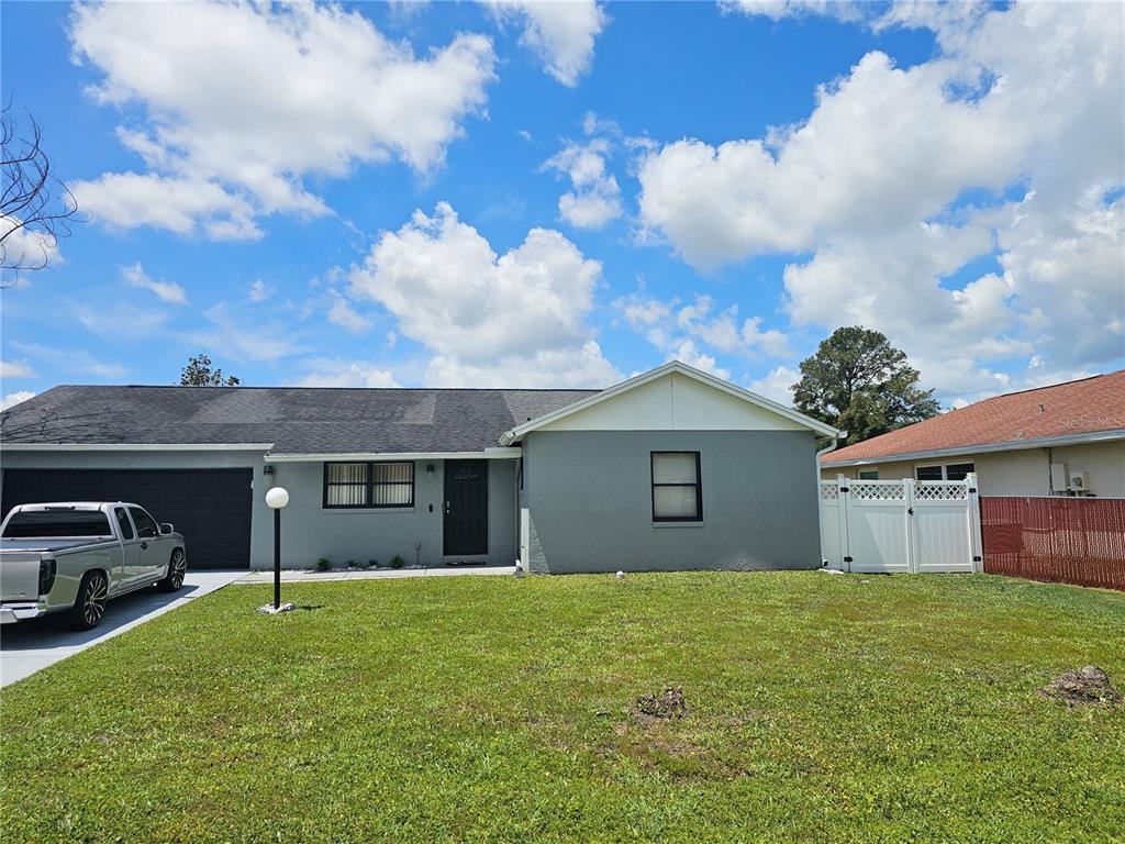 A single-story gray house with a dark roof, a garage, and a front lawn — 724 DEL RAY DRIVE, KISSIMMEE, FL
