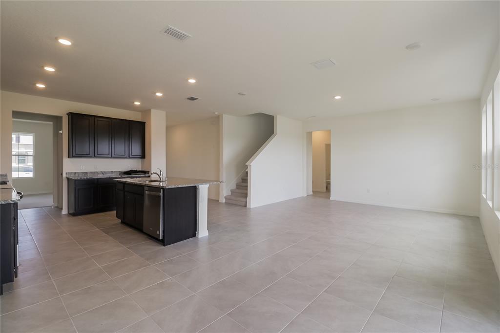 An open-concept kitchen with dark cabinets and a large island overlooks a spacious tiled area — 10832 CHARLOTTE DRIVE, PARRISH, FL