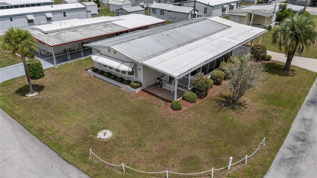 An aerial view of a manufactured home with a metal roof and a screened porch — 36957 GRACE AVENUE, ZEPHYRHILLS, FL