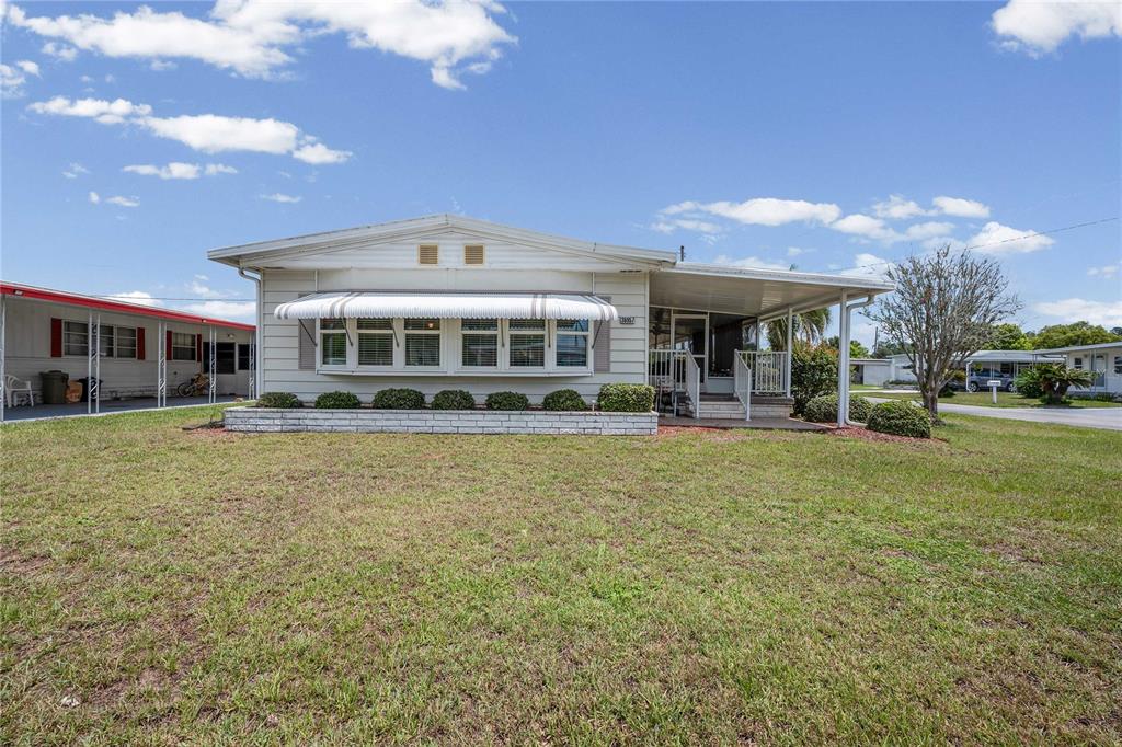 A single-story manufactured home with a white exterior, front awning, and attached carport — 36957 GRACE AVENUE, ZEPHYRHILLS, FL