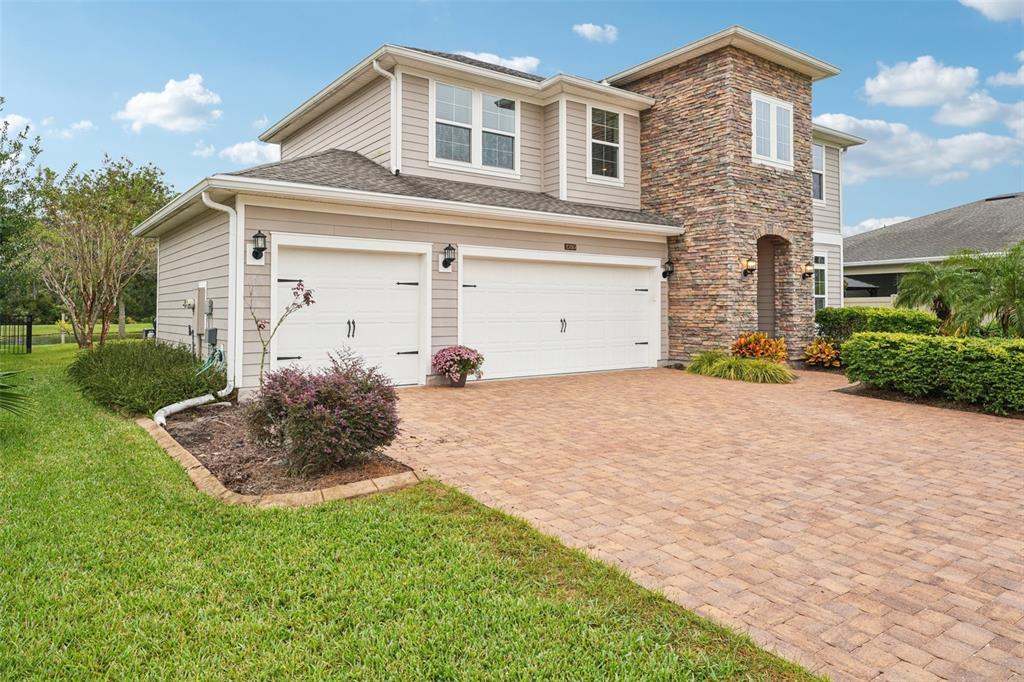 A two-story house with a stone facade, beige siding, and a paved driveway — 2785 LAS CALINAS BOULEVARD, ST AUGUSTINE, FL