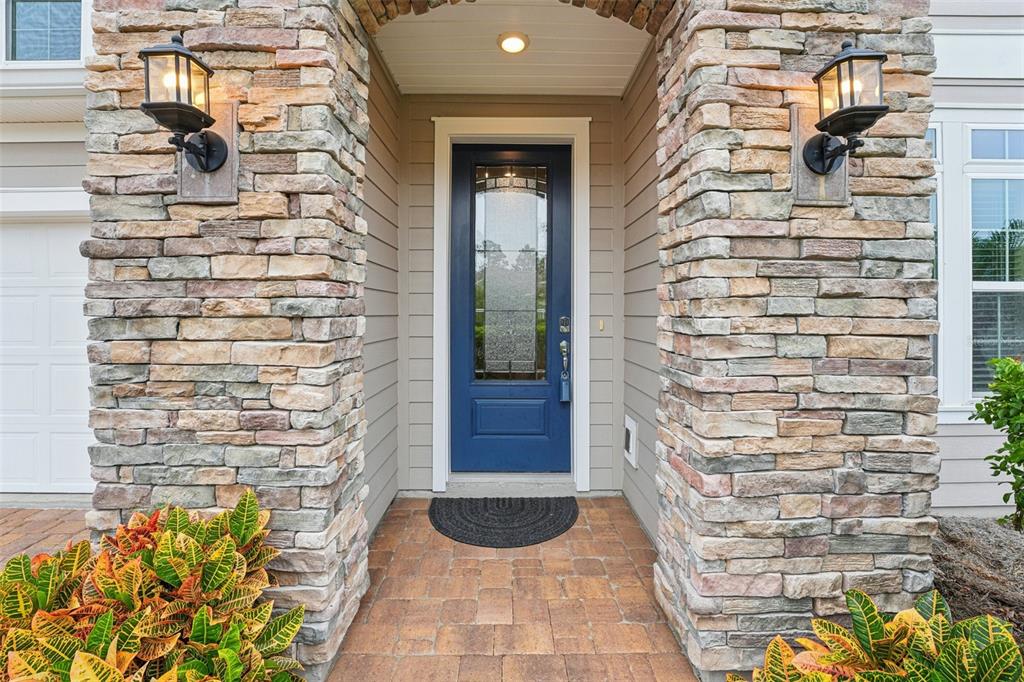 A blue front door is framed by stone pillars and flanked by two outdoor wall lanterns — 2785 LAS CALINAS BOULEVARD, ST AUGUSTINE, FL