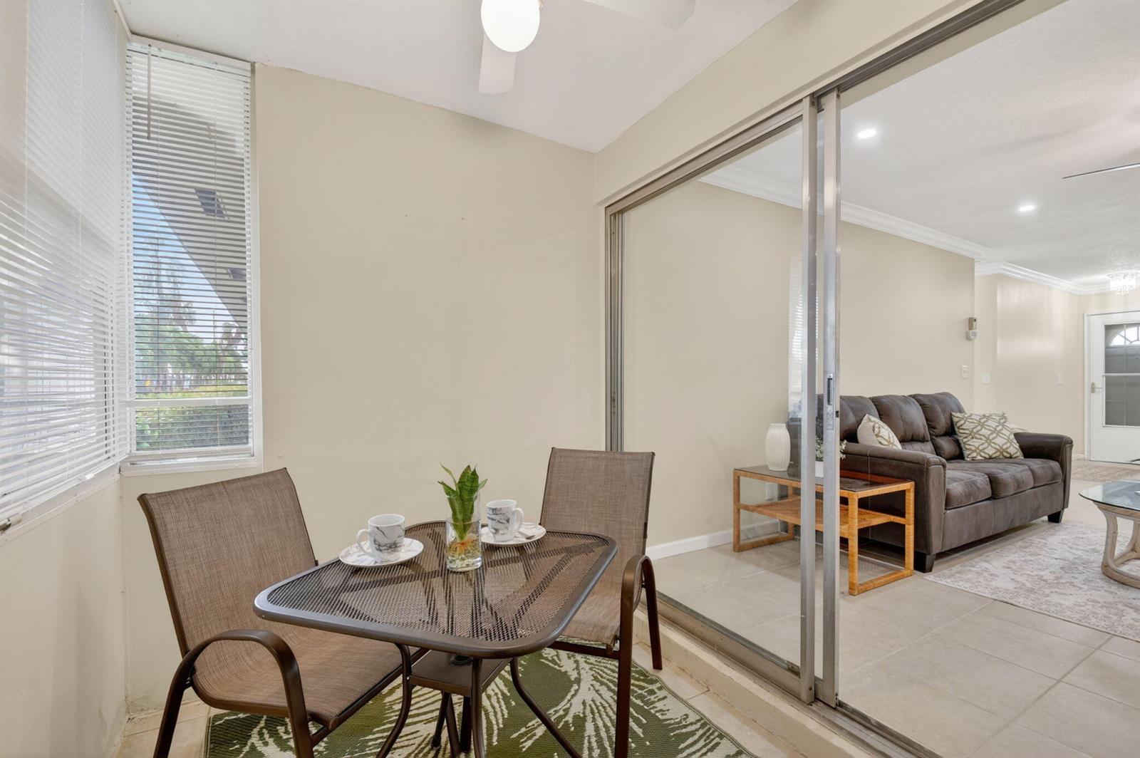 A small patio with a metal table and chairs overlooks a living room through glass doors — 2787 Dudley Dr Apt D, West Palm Beach FL 33415, WEST PALM BEACH, FL