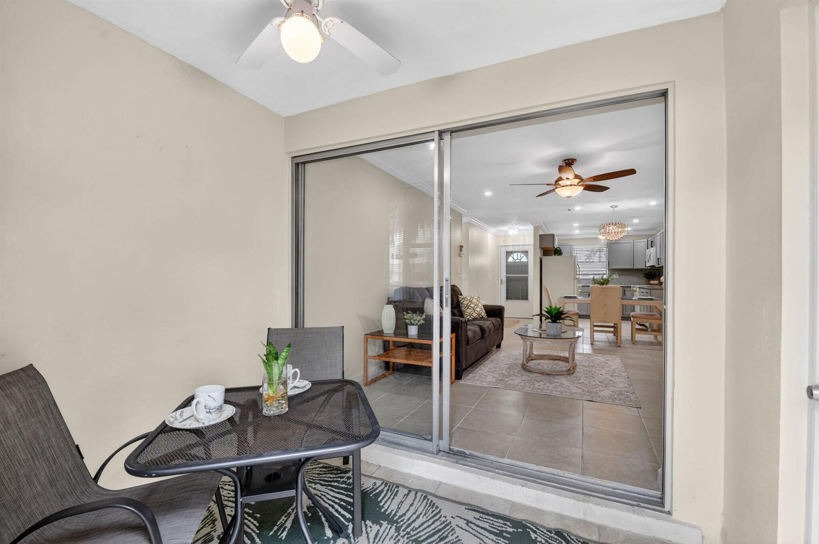 A patio with a small table and chairs overlooks an interior living and dining area — 2787 Dudley Dr Apt D, West Palm Beach FL 33415, WEST PALM BEACH, FL