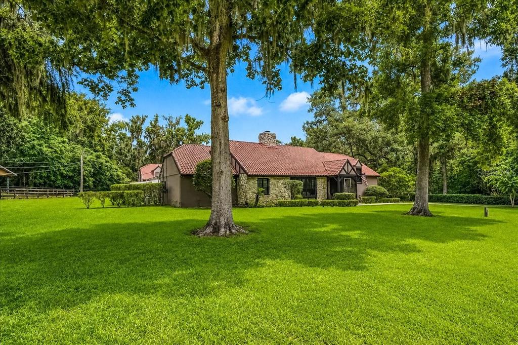 An aerial view shows a house with a red tile roof, pool, and surrounding lawn — 411 SW 38TH STREET, OCALA, FL
