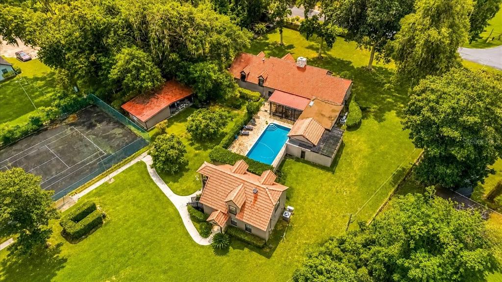 A single-story house with a red tile roof, stone facade, and large lawn with trees — 411 SW 38TH STREET, OCALA, FL