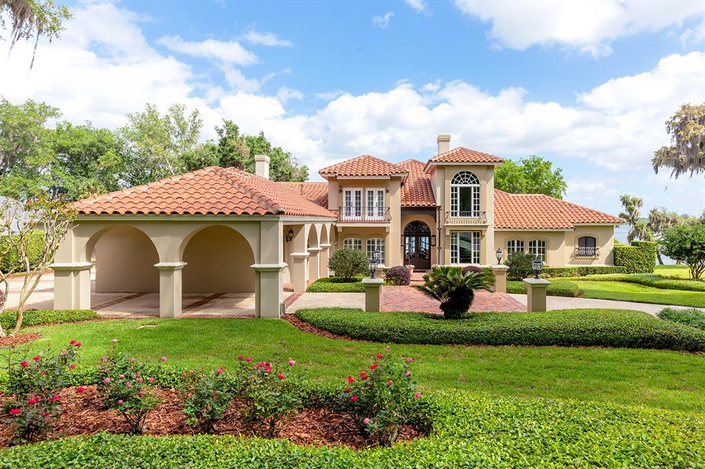 A two-story Mediterranean-style house with a tile roof, arched porte-cochère, and landscaped front yard — 1351 N CLASSIC COURT, LONGWOOD, FL