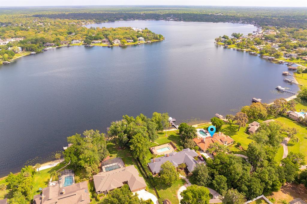 An aerial view shows a waterfront house with a pool and dock on a lake — 1351 N CLASSIC COURT, LONGWOOD, FL