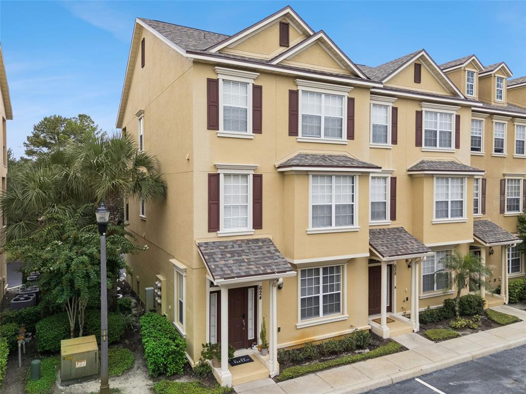 A three-story yellow townhouse with brown shutters and a small covered entryway — 624 PENSACOLA LANE, LAKE MARY, FL