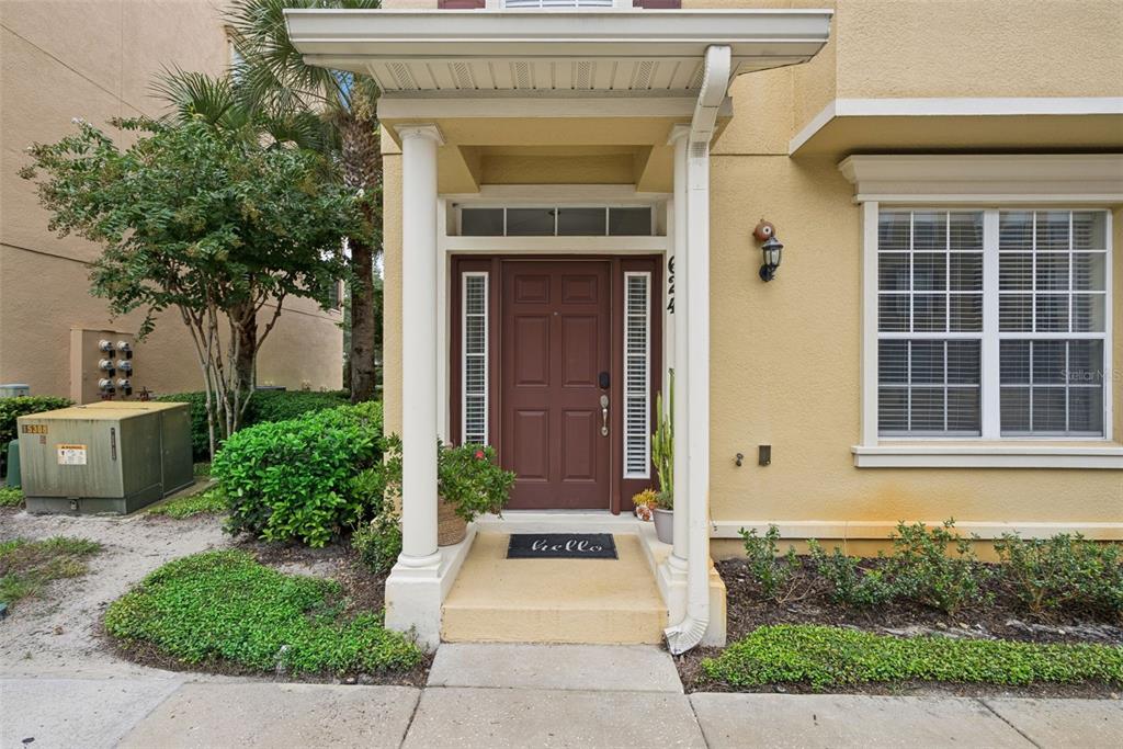 The exterior entrance of a tan building features a brown front door and white columns — 624 PENSACOLA LANE, LAKE MARY, FL