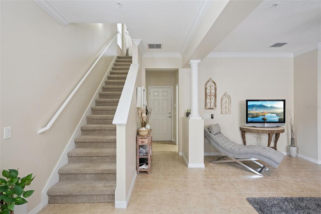 A carpeted staircase leads to an upper level next to a tiled entryway and lounge — 624 PENSACOLA LANE, LAKE MARY, FL