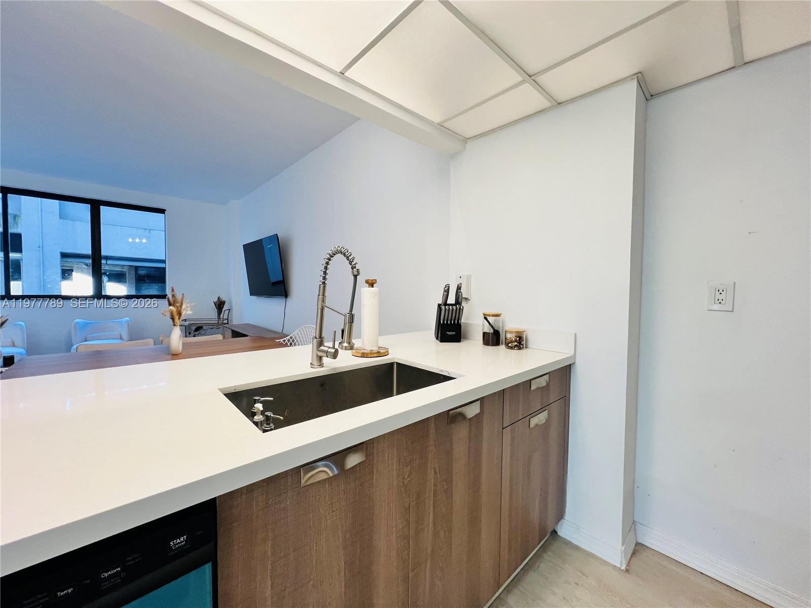 A kitchen features wood-toned cabinets, a white countertop, a stainless steel sink, and a faucet — 540 Brickell Key Dr # 202, Miami FL 33131, MIAMI, FL