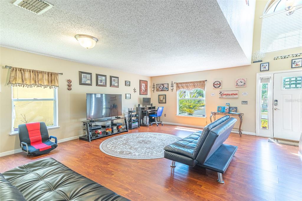 A living room features wood-look flooring, a black futon, a television, and a desk area — 407 SAMUEL STREET, DAVENPORT, FL