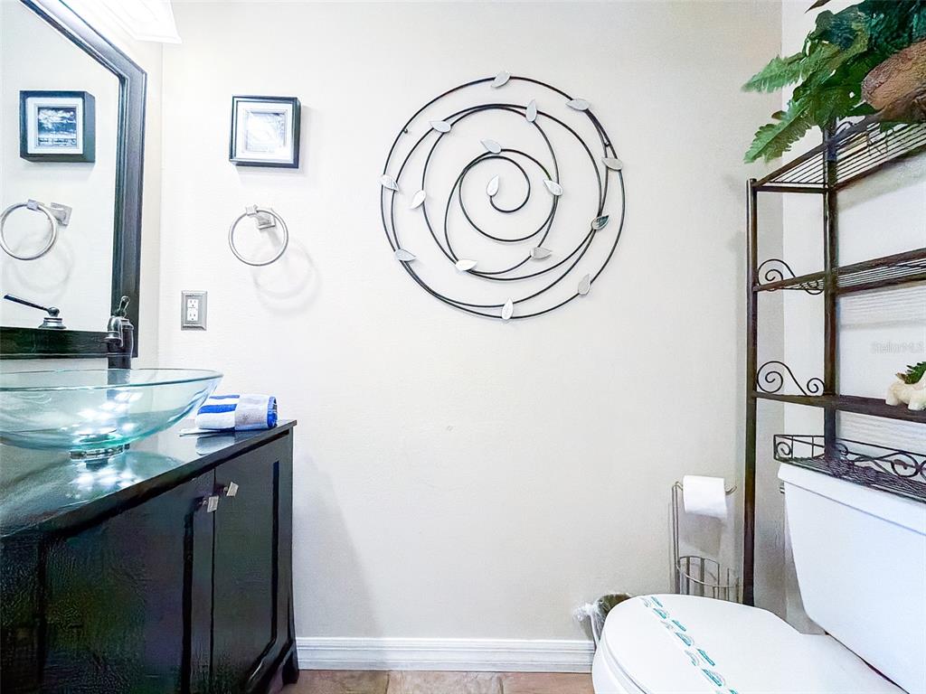 A bathroom features a glass vessel sink, dark vanity, metal wall art, and a toilet — 407 SAMUEL STREET, DAVENPORT, FL
