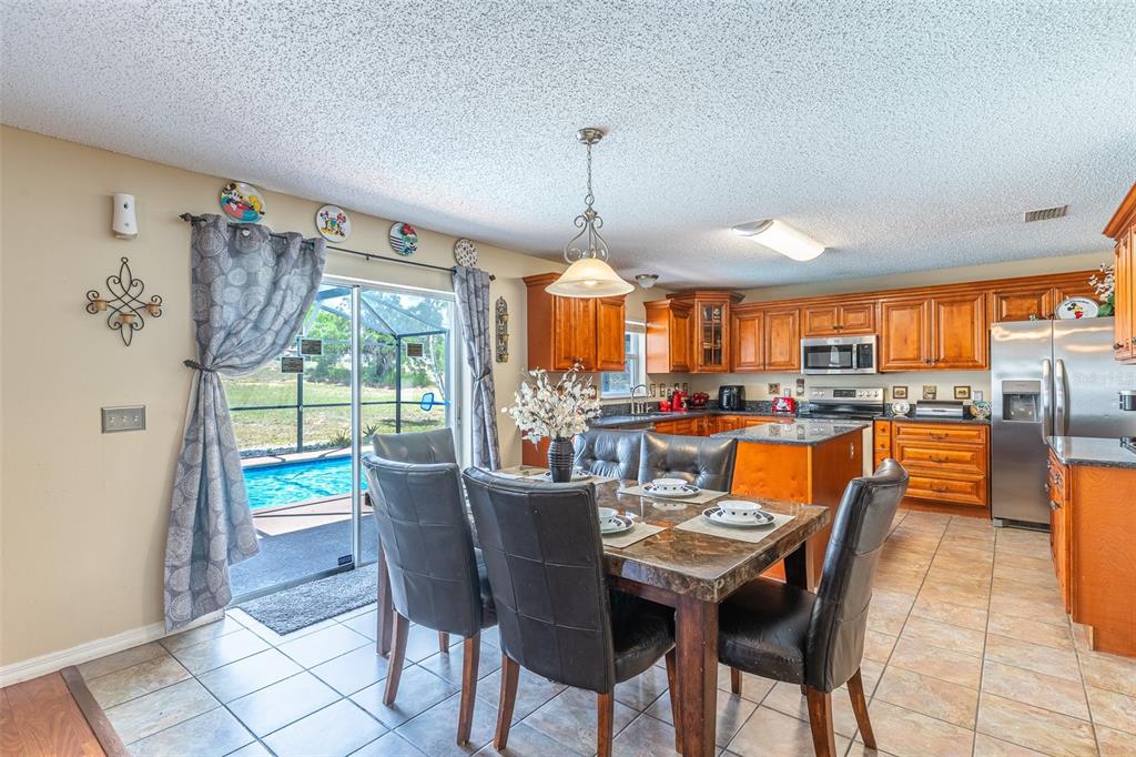 A dining area with a marble-topped table sits adjacent to a kitchen and pool patio — 407 SAMUEL STREET, DAVENPORT, FL