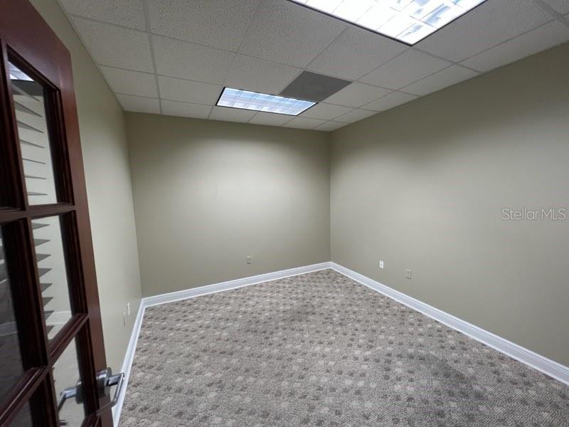 An empty office features beige walls, a patterned carpet, and a drop ceiling with lights — 1325 S INTERNATIONAL PKWY UNIT 2221, LAKE MARY, FL
