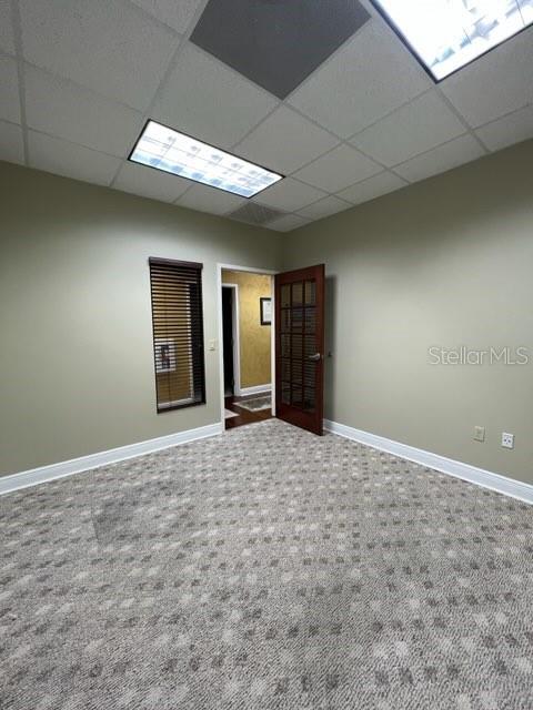 An office room features beige walls, a patterned carpet, a glass-paneled door, and recessed lighting — 1325 S INTERNATIONAL PKWY UNIT 2221, LAKE MARY, FL