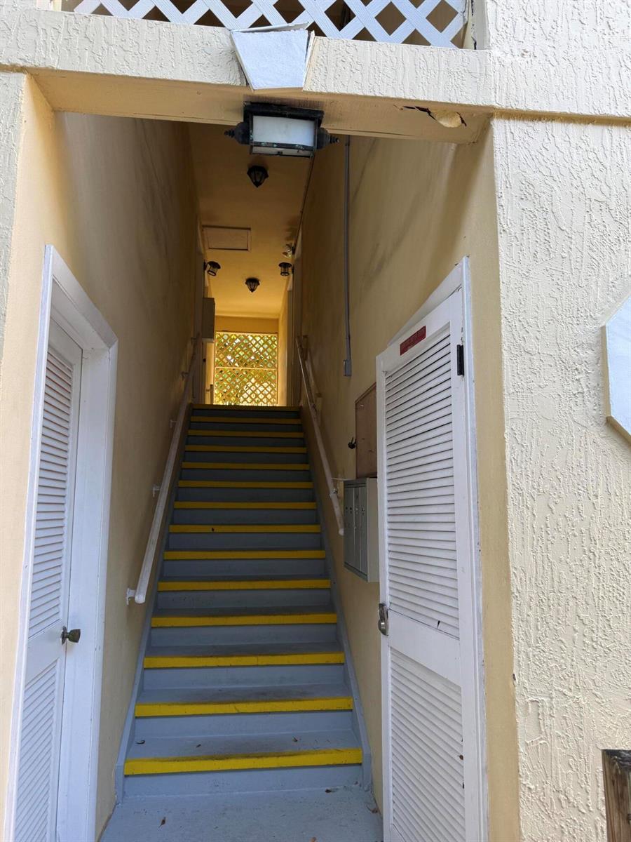 A set of outdoor stairs with yellow-striped treads leads up to a lattice-covered landing — 320 SE 10th Street # C, Pompano Beach FL 33060, POMPANO BEACH, FL
