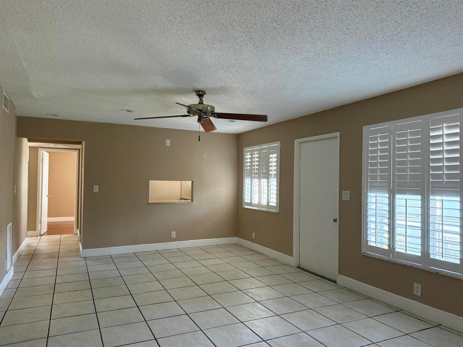 A room with beige walls, white tile flooring, a ceiling fan, and plantation shutters — 320 SE 10th Street # C, Pompano Beach FL 33060, POMPANO BEACH, FL