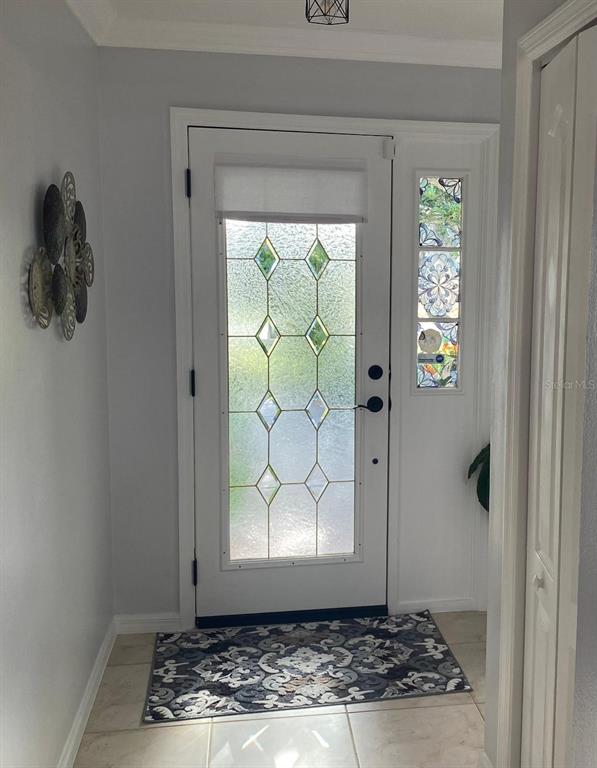 An entryway features a white front door with a diamond-patterned glass insert and tile flooring — 8437 GIBRALTER STREET, SPRING HILL, FL