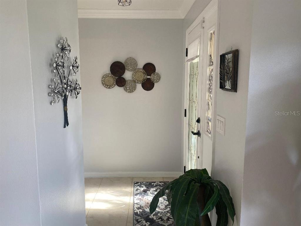 An entryway features light gray walls, tile flooring, a decorative wall sculpture, and a glass-paneled door — 8437 GIBRALTER STREET, SPRING HILL, FL