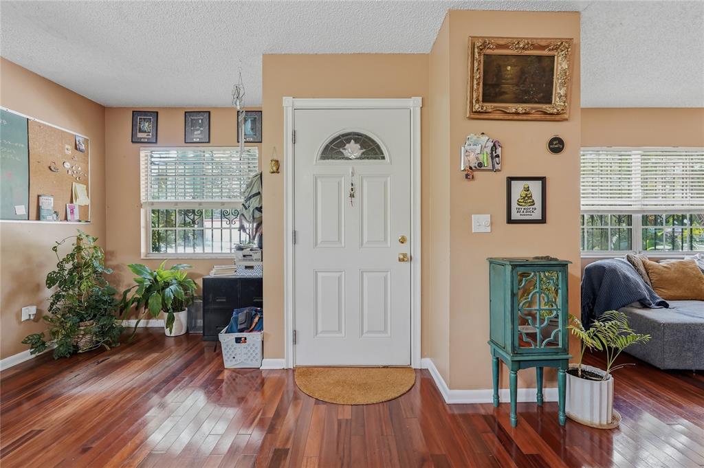 A bright entryway features hardwood floors, a white front door, and tan walls — 12922 N ALBANY AVENUE, TAMPA, FL