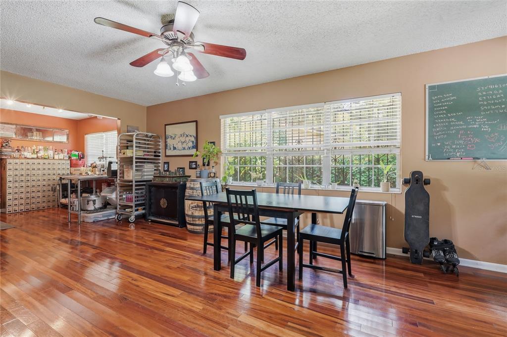 A dining area with hardwood floors, a ceiling fan, and a large window — 12922 N ALBANY AVENUE, TAMPA, FL