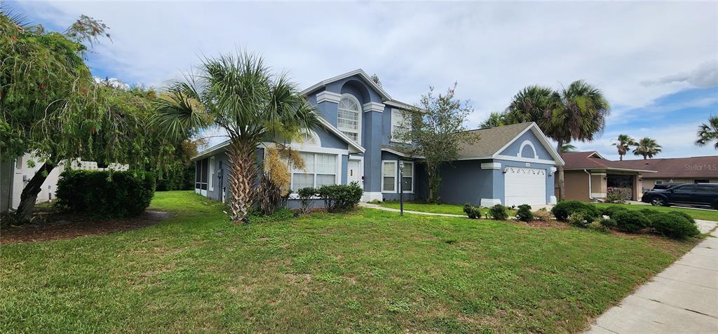 A two-story blue house with a white garage and palm trees in the front yard — 14613 LONE EAGLE DRIVE, ORLANDO, FL