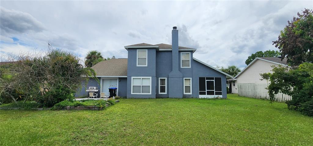 The rear exterior of a two-story blue house features a chimney and a screened porch — 14613 LONE EAGLE DRIVE, ORLANDO, FL
