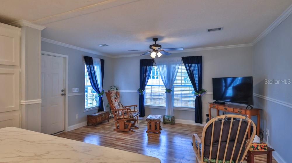 A living room features hardwood floors, a ceiling fan, and two rocking chairs — 1157 MILLBROOK AVENUE, PORT ORANGE, FL