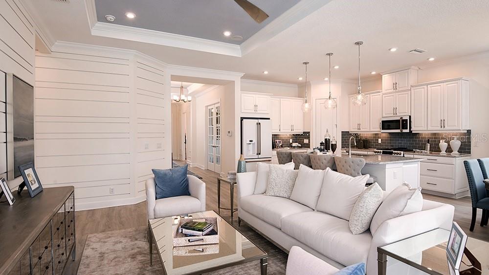 A modern kitchen features white cabinets, granite countertops, a gray subway tile backsplash, and stainless appliances — 3208 VICENZA COURT, BRADENTON, FL