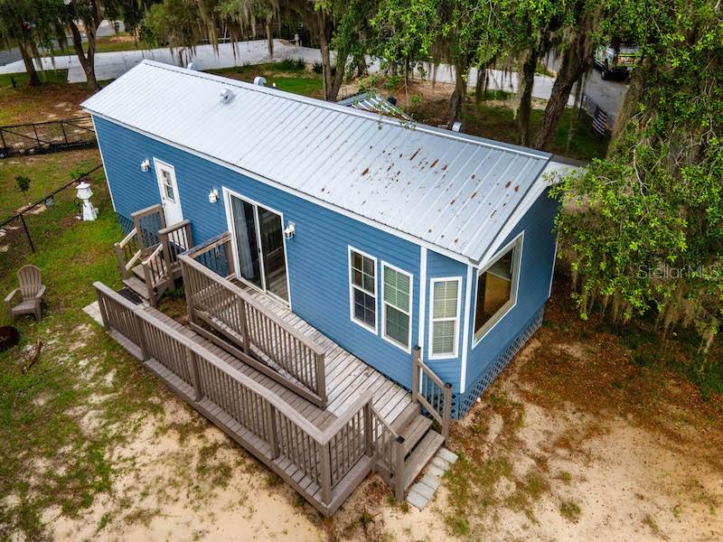 An aerial view of a blue tiny home with a metal roof and wooden deck — 15991 NE 243RD PLACE ROAD UNIT 31, FORT MC COY, FL