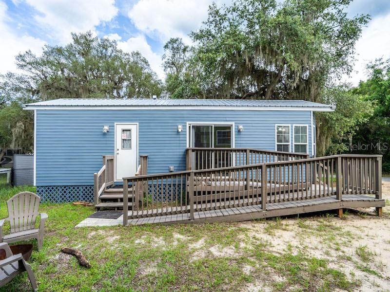 A blue mobile home features a wooden ramp leading to a sliding glass door — 15991 NE 243RD PLACE ROAD UNIT 31, FORT MC COY, FL