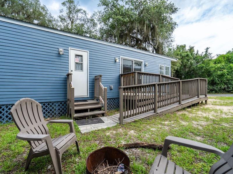 A blue mobile home features a wooden wheelchair ramp leading to a side entrance door — 15991 NE 243RD PLACE ROAD UNIT 31, FORT MC COY, FL