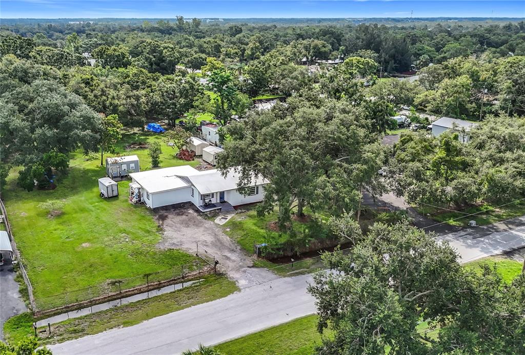 An aerial view shows a white house with a metal roof surrounded by trees — 8016 FORMBY STREET, RIVERVIEW, FL