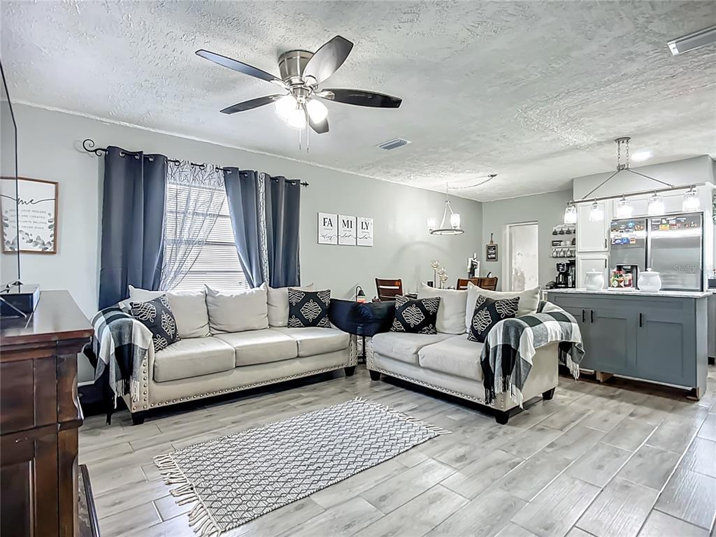 A living room features two light-colored sofas, a ceiling fan, and wood-look tile flooring — 8016 FORMBY STREET, RIVERVIEW, FL