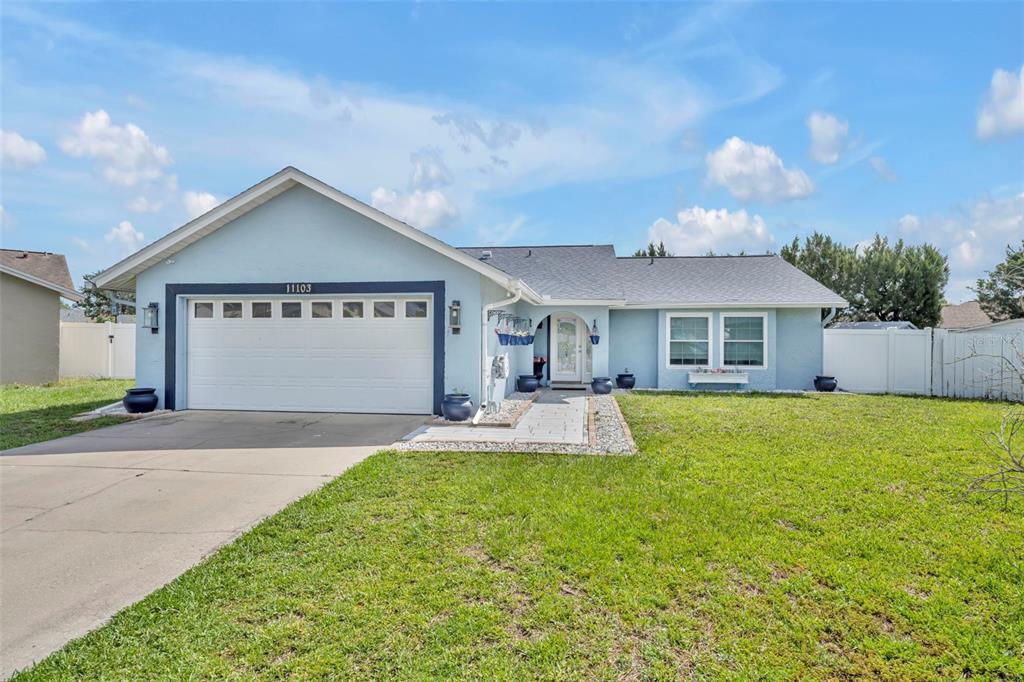 A light blue single-story house features a two-car garage and a front walkway — 11103 ARIES DRIVE, ORLANDO, FL