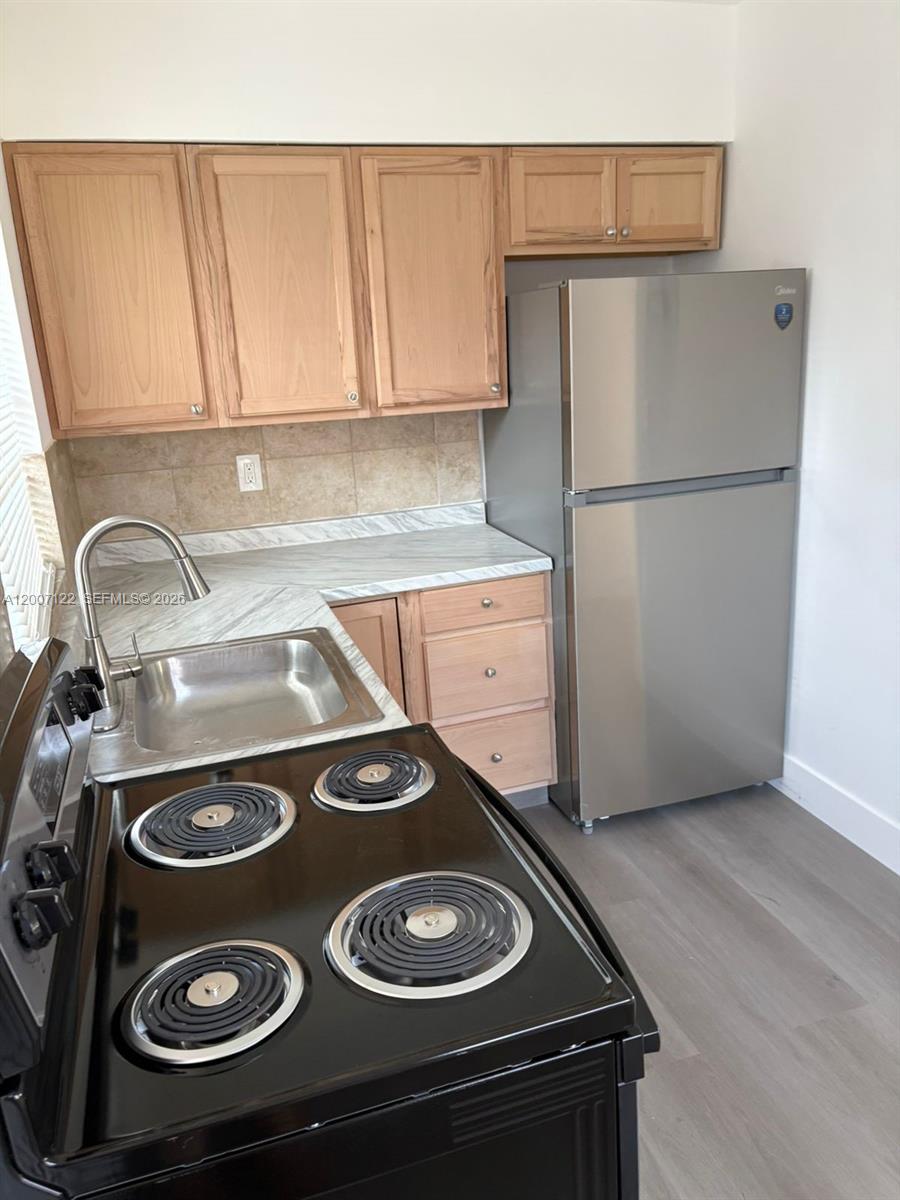 A kitchen features light wood cabinets, a stainless steel refrigerator, and a black electric stove — 2316 Madison St # 6, Hollywood FL 33020, HOLLYWOOD, FL