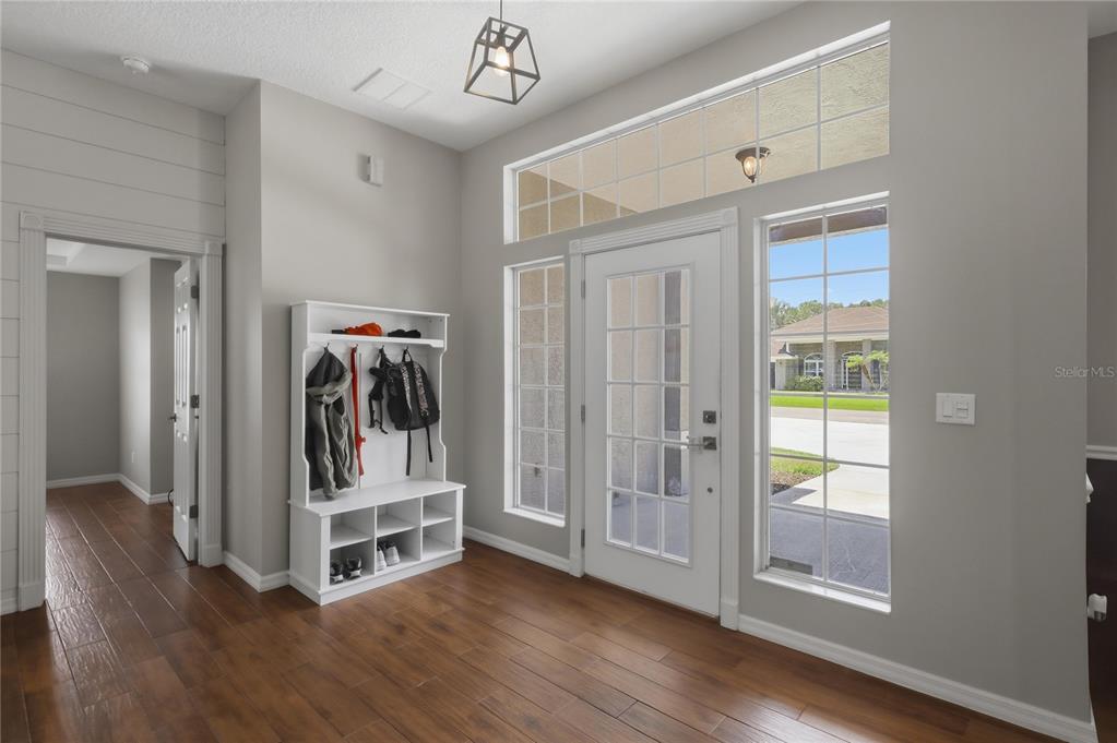 An entryway features a white coat rack, wood-look flooring, and a door with sidelights — 62 SENTINEL TRAIL, PALM COAST, FL