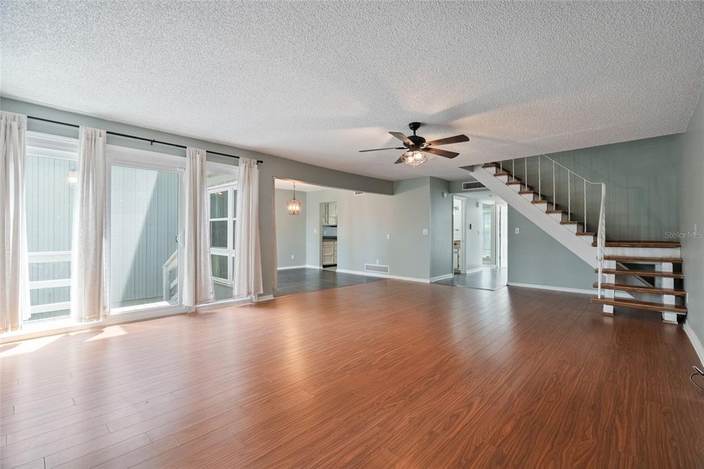 A living room with wood-look flooring, a ceiling fan, and a staircase with white railings — 1923 LAKE ALDEN DRIVE UNIT A, APOPKA, FL