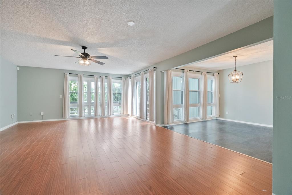 A living room with wood-look flooring, a ceiling fan, and large windows with white curtains — 1923 LAKE ALDEN DRIVE UNIT A, APOPKA, FL