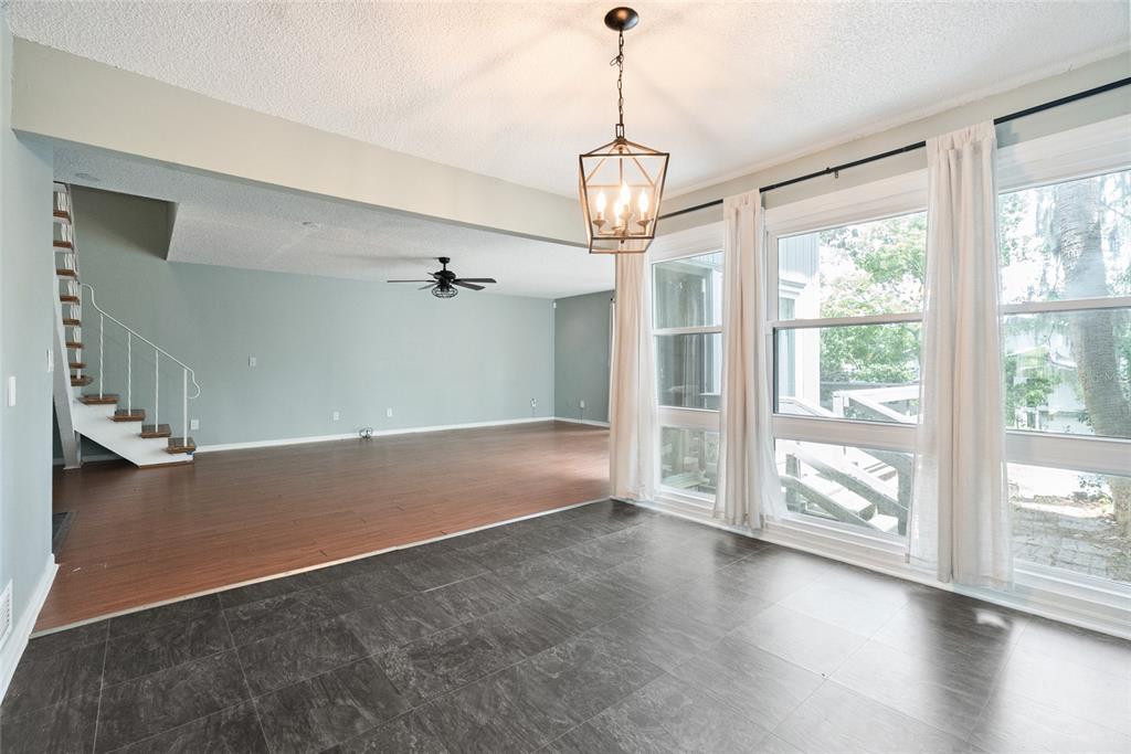 A dining area with dark tile floors transitions into a living room with wood flooring — 1923 LAKE ALDEN DRIVE UNIT A, APOPKA, FL